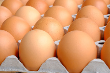 A dozen brown eggs in a carton on a wooden table