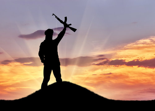 Silhouette of man standing with rifle during sunset