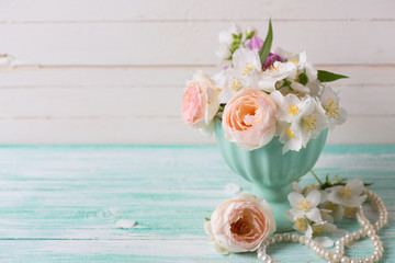 Pastel  roses and jasmine flowers  in vase on turquoise wooden b