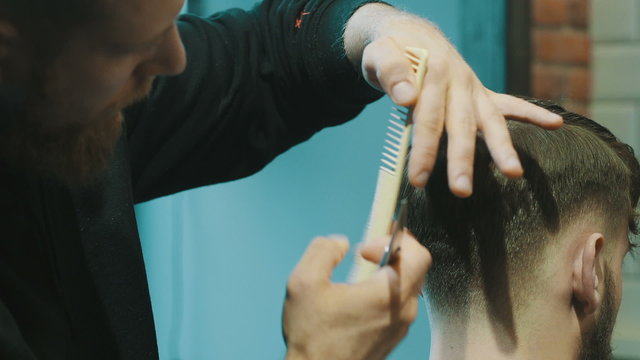 Barber cuts the hair of the client with scissors