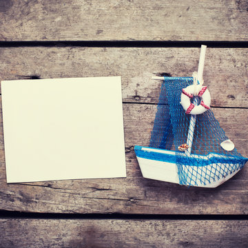 Decorative sailing boat and empty tag on  vintage wooden backgro
