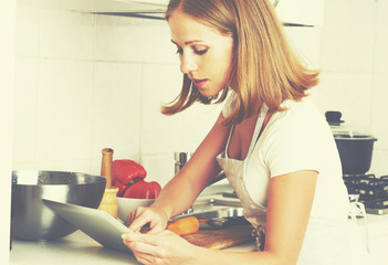 woman housewife cooks food a recipe from Internet with a tablet