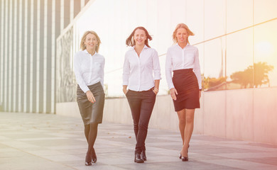Three happy business women walking in the far 
