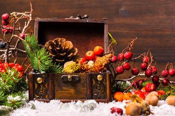 Christmas winter composition with chest, apple, nuts, cones, ber