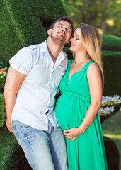 Fototapeta premium Beautiful young pregnant couple in the park
