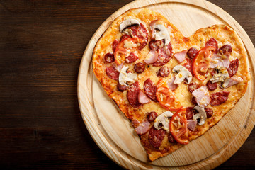 Pizza heart shape on dark wooden background top view