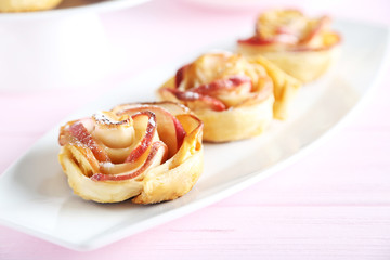 Obraz na płótnie Canvas Fresh puff pastry with apple shaped roses on pink wooden table