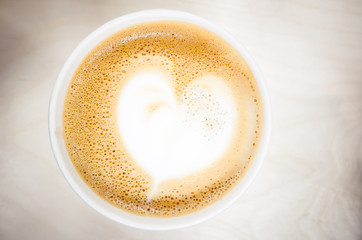Cup of cappuccino coffee with heart shaped milk foam