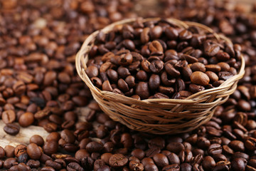 Roasted coffee beans in basket on a brown wooden background