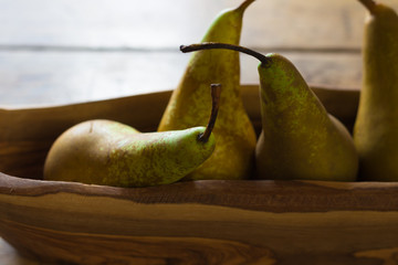 Four conference pears in a wooden bowl