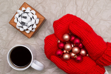 Christmas balls in hands, a cup of coffee and gift