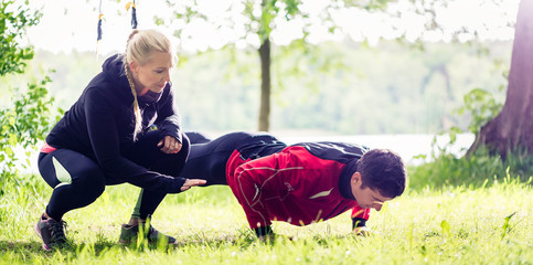 Sportliches Paar mit Sling Trainer outdoors