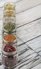 Dried herbal tea lavender, chamomile, linden flower, hibiscus, rooibos, Japanese green tea in mason jar over wooden background