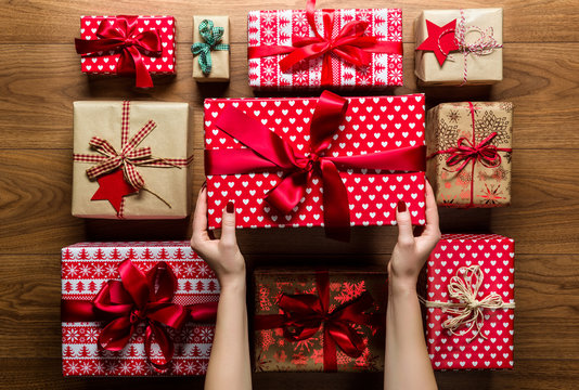 Woman organising beautifuly wrapped vintage christmas presents on wooden background, view from above