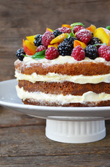 Naked cake with cream, decorated with raspberries, blackberries, peaches 
