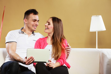 couple with tablet sitting on couch at home