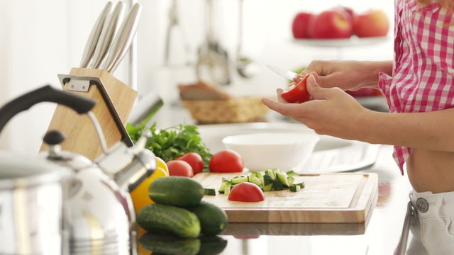 Young woman chopping vegetables in kitchen