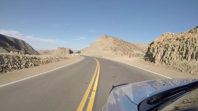 Front view of car driving on the famous paved road Route 40 parallel to the Andes against a blue sky and going towards the Ischigualasto National Park, San Juan Province. Argentina 2014