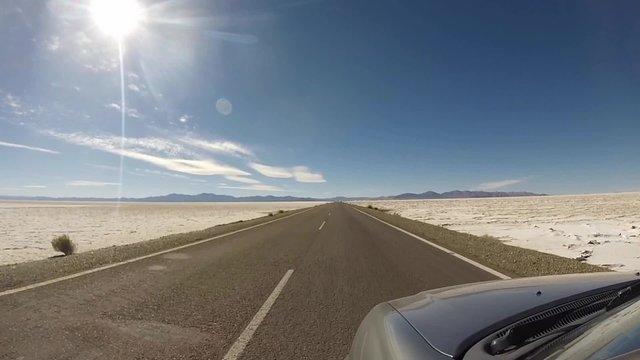 Front view of car driving the famous Route 40 paved road parallel to the Andes against a blue sky and going towards the Salinas Grande, Jujuy Province. Argentina 2014