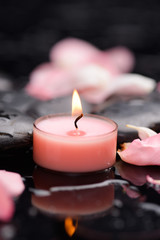 Beautiful pink rose petals with candle and therapy stones 