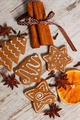 Fresh baked decorated gingerbread with spices on old wooden background, christmas time
