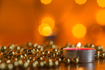 Burning candle and Christmas ornaments with bokeh in the background
