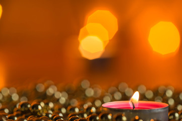 Burning candle and Christmas ornaments with bokeh in the background