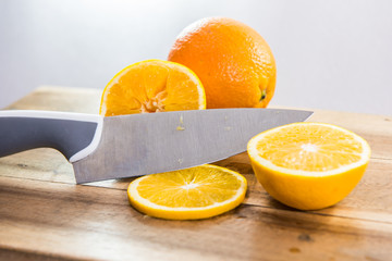 Obraz na płótnie Canvas Sliced orange with knife on wooden chopping block