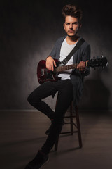 Fototapeta premium fit artist playing guitar in studio while sitting