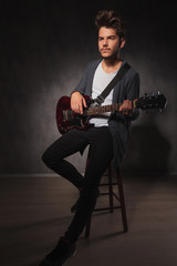 Fototapeta premium skinny rocker playing guitar while sitting and looking away