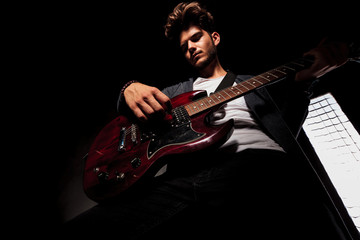 Obraz premium artist in dark backgroud playing guitar