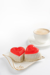 Two cakes in the shape of a heart and a cup of coffee on a white table/ Morning coffee with love