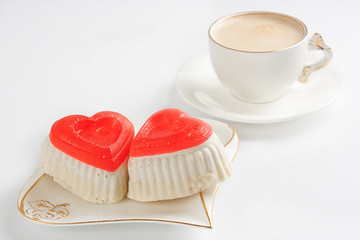 Two cakes in the shape of a heart and a cup of coffee on a white table/ Morning coffee with love