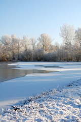 Dutch snow landscape with frozen lake and trees