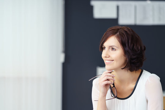gesch&auml;fsfrau im b&uuml;ro l&auml;chelt in gedanken