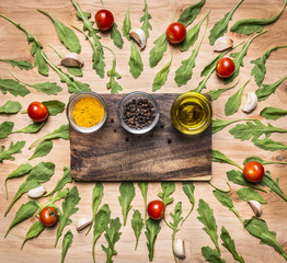 cutting board with spices and butter, with arugula leaves around  place for text, frame on wooden rustic background top view