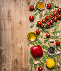 border with oil, cherry tomatoes on a branch, pepper, seasoning, arugula, garlic border ,with text area on wooden rustic background top view