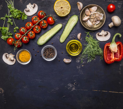 Ingredients for cooking vegetarian food tomatoes on a branch, herbs, cucumber, lemon, garlic, oil, black pepper, paprika, mushrooms, border ,with text area on wooden rustic background top view