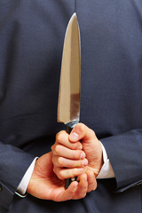 Hand hält Messer hinter dem Rücken