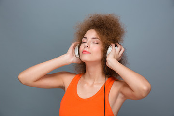 Curly woman with eyes closed in headphones listening to music