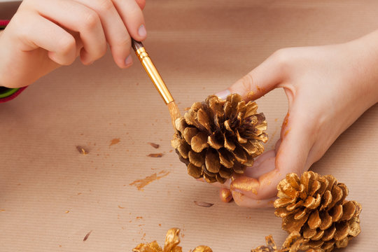 Child painting pine cones