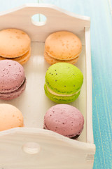 Set of various colored macaroons on wooden plate