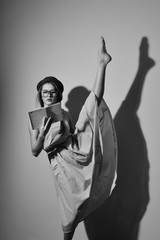 Portrait of elegant gymnast in a hat and glasses reading a book
