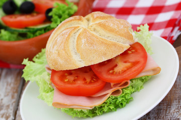 Bread roll with smoked ham, lettuce and tomatoes
