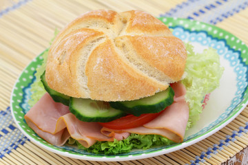 Bread roll with ham, lettuce, tomato and cucumber, closeup
