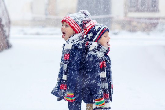 Two happy little boys having fun with snow in winter