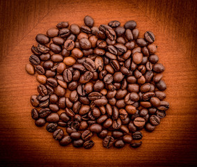 Heap of coffee beans on the brown table. Image taken from above.
