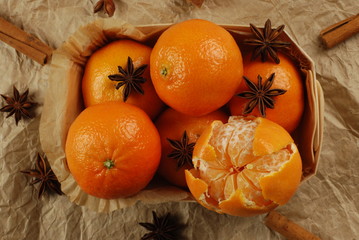 Clementine fruits in wooden basket with spicy cinnamon, anis on a crumpled vintage paper.