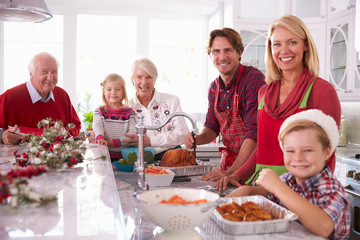 Extended Family Group Basting Christmas Turkey In Kitchen
