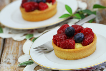 Delicious crunchy tartelette with custard, fresh raspberries and blueberries, closeup
